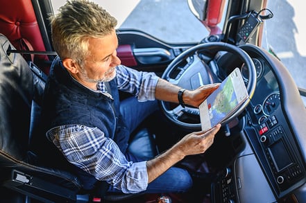 man with beard, flannel shirt and vest at steering wheel with tablet ascend telematics ELD software