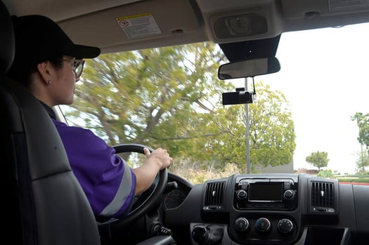Woman in purple shirt at steering wheel of vehicle with surfsite dashcam facing her